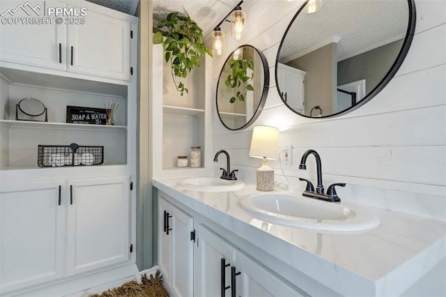 bathroom featuring a textured ceiling and double vanity