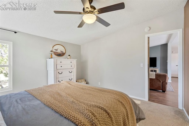 carpeted bedroom featuring a textured ceiling, ceiling fan, and baseboards