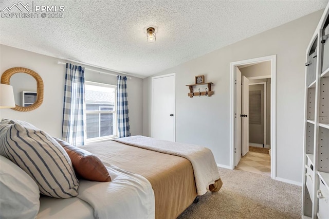 bedroom with light carpet, a textured ceiling, and baseboards
