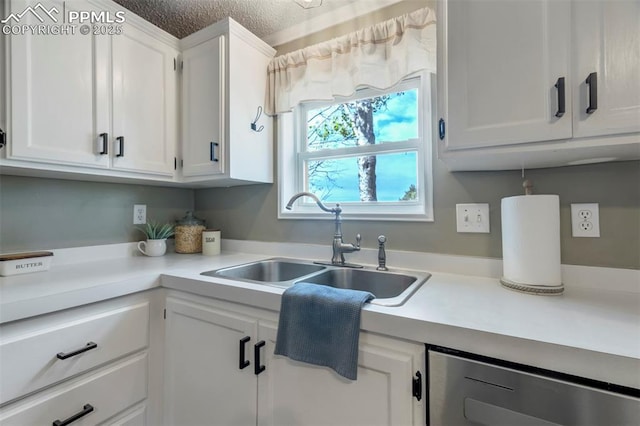 kitchen featuring a sink, dishwasher, white cabinets, light countertops, and a textured ceiling