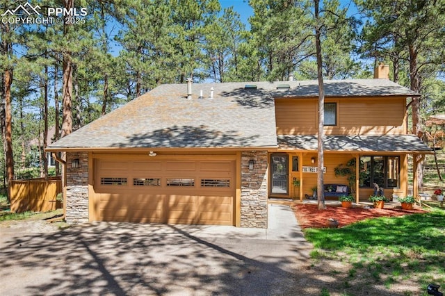 18045 Woodhaven Pl, Colorado Springs, CO 80908 - view of front of home featuring stone siding, an attached garage, asphalt driveway, and a chimney