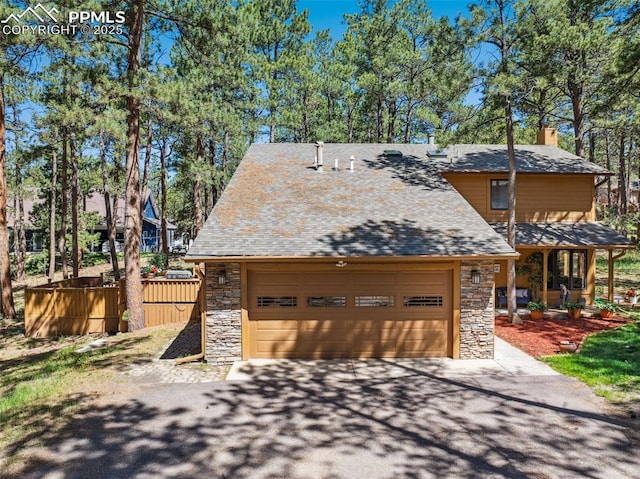 18045 Woodhaven Pl, Colorado Springs, CO 80908 - view of front facade featuring stone siding, a chimney, driveway, and fence
