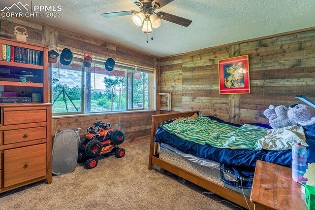 2760 Evergreen Rd, Colorado Springs, CO 80921 - carpeted bedroom featuring wood walls, a textured ceiling, and ceiling fan