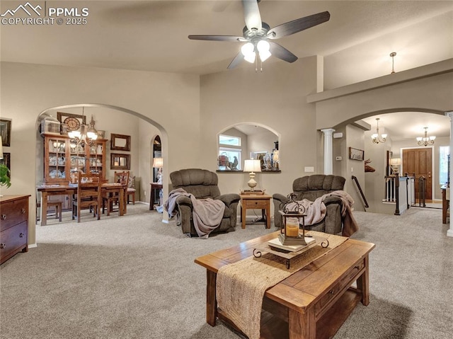 carpeted living room with arched walkways, a chandelier, and a ceiling fan