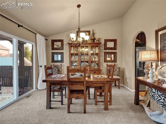 dining room with lofted ceiling, light carpet, arched walkways, a chandelier, and baseboards