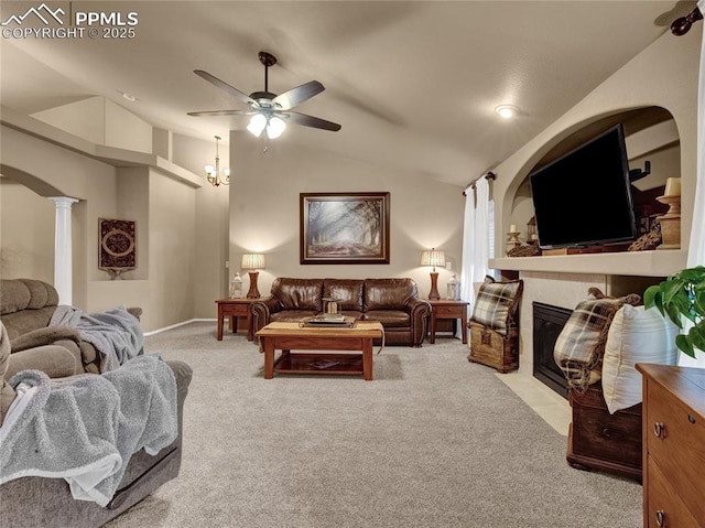 carpeted living room featuring lofted ceiling, ceiling fan, decorative columns, a tiled fireplace, and arched walkways