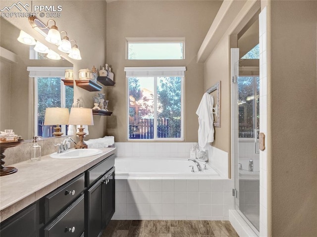 bathroom featuring vanity, a shower stall, a garden tub, and wood finished floors