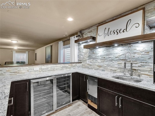 kitchen featuring beverage cooler, a sink, decorative backsplash, and light stone counters