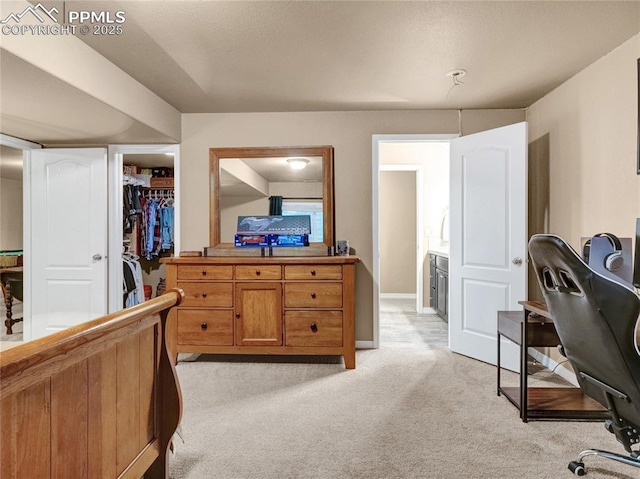 bedroom featuring light colored carpet, a walk in closet, and a closet