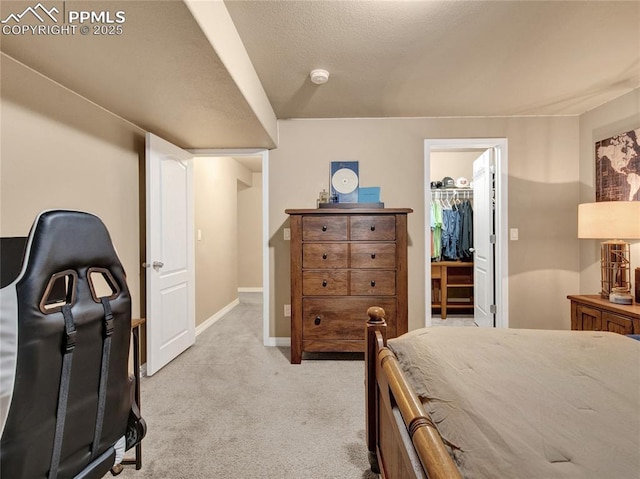 bedroom featuring light colored carpet, a spacious closet, baseboards, and a closet