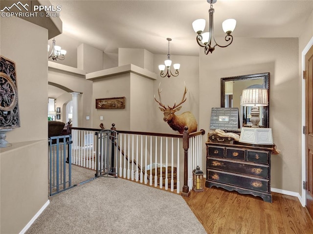 corridor with a chandelier, an upstairs landing, arched walkways, and baseboards