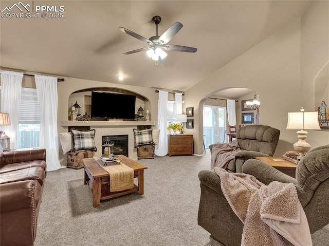 living room featuring arched walkways, lofted ceiling, ceiling fan, carpet, and a chandelier