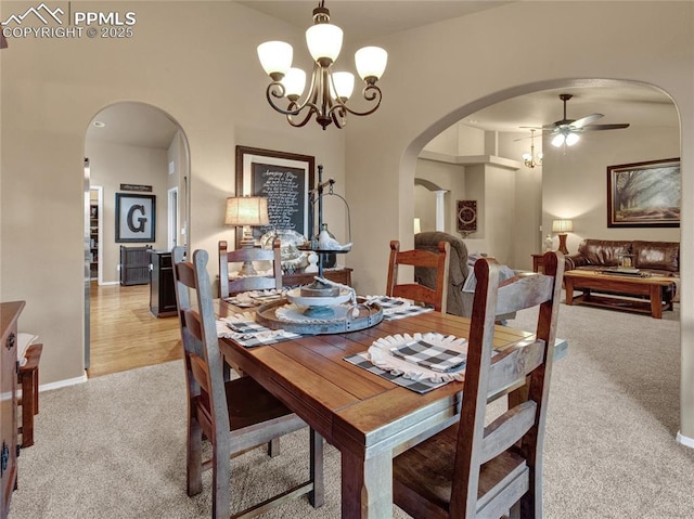 dining area with arched walkways, carpet flooring, ceiling fan, a chandelier, and baseboards
