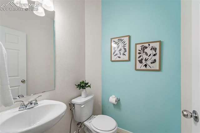 bathroom with a sink, toilet, and baseboards