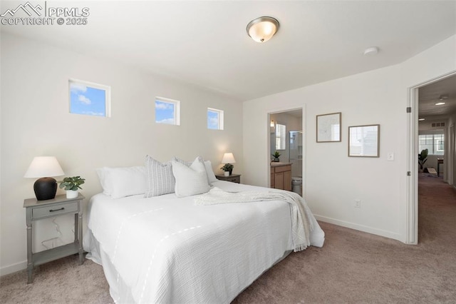 bedroom featuring light colored carpet, baseboards, and ensuite bathroom