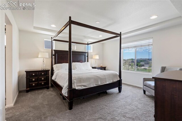 carpeted bedroom with recessed lighting, baseboards, and a raised ceiling