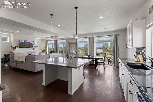 kitchen with a sink, dark stone countertops, stainless steel range with electric cooktop, white cabinets, and dark wood-type flooring