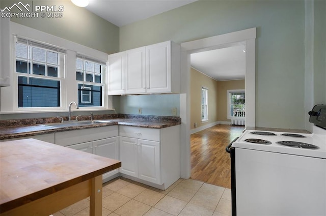 1505 Cheyenne Blvd, Colorado Springs, CO 80906 - kitchen with white electric range, a sink, white cabinets, light tile patterned flooring, and radiator heating unit