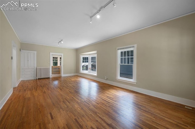 1505 Cheyenne Blvd, Colorado Springs, CO 80906 - empty room with track lighting, radiator, ornamental molding, wood finished floors, and baseboards