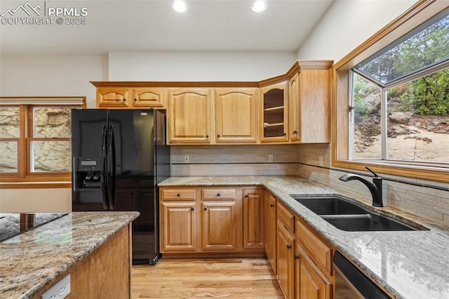 1433 Ledge Rock Ter, Colorado Springs, CO 80919 - kitchen featuring black appliances, a sink, light stone countertops, light wood-style flooring, and glass insert cabinets