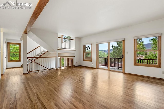 1433 Ledge Rock Ter, Colorado Springs, CO 80919 - unfurnished living room featuring wood finished floors, baseboards, and stairway