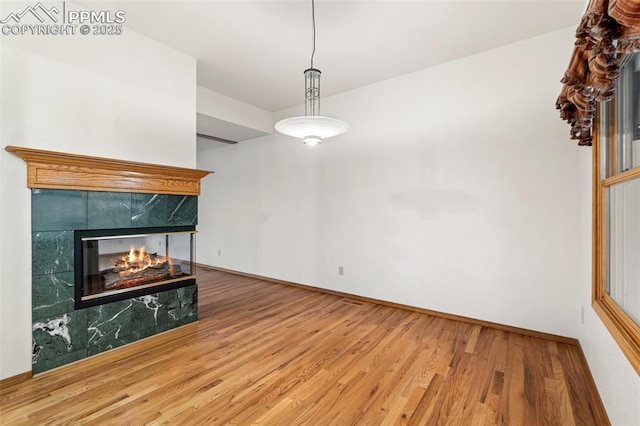 1433 Ledge Rock Ter, Colorado Springs, CO 80919 - unfurnished living room featuring wood finished floors, a tiled fireplace, and baseboards