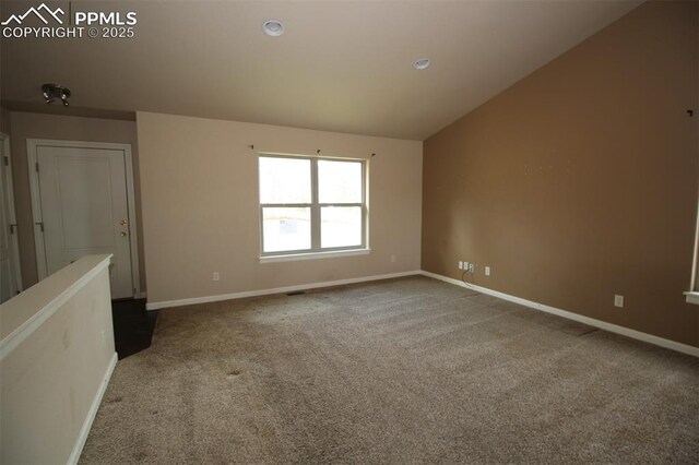 carpeted empty room with baseboards and lofted ceiling