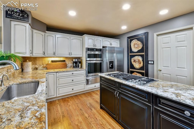8005 Hedgewood Way, Colorado Springs, CO 80919 - kitchen with a warming drawer, stainless steel appliances, white cabinets, a sink, and light wood finished floors