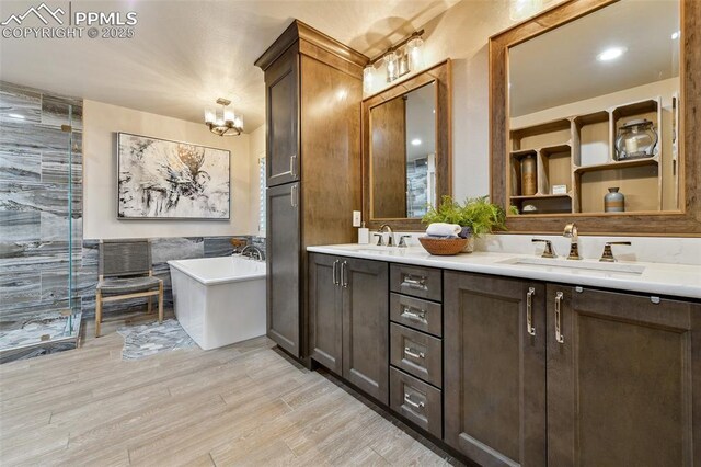 8005 Hedgewood Way, Colorado Springs, CO 80919 - full bathroom featuring wood finished floors, a soaking tub, double vanity, a stall shower, and a chandelier
