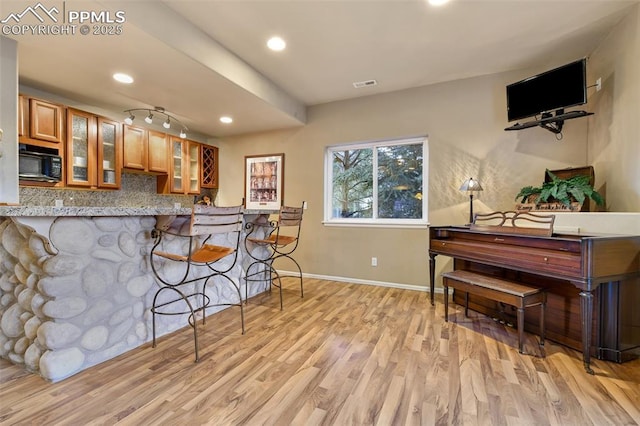 8005 Hedgewood Way, Colorado Springs, CO 80919 - kitchen with black microwave, brown cabinets, light wood-type flooring, baseboards, and tasteful backsplash