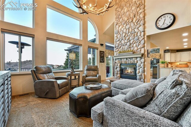 8005 Hedgewood Way, Colorado Springs, CO 80919 - living room with a chandelier, a towering ceiling, carpet floors, a stone fireplace, and baseboards