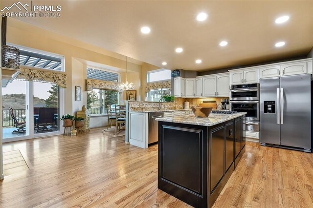 8005 Hedgewood Way, Colorado Springs, CO 80919 - kitchen with stainless steel appliances, white cabinetry, a peninsula, a kitchen island, and light stone countertops