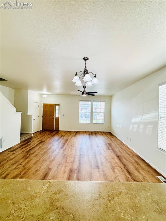 10525 Wells Pt, Fountain, CO 80817 - unfurnished living room featuring a chandelier, wood finished floors, and baseboards