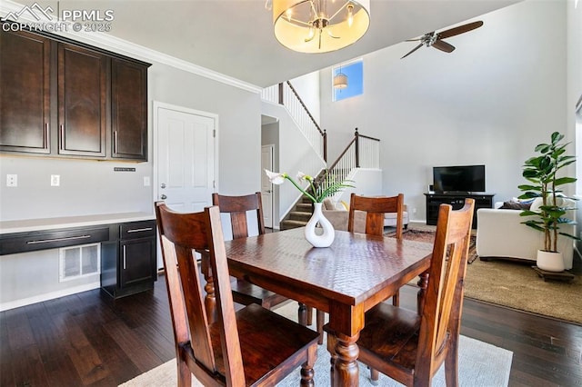 dining space featuring stairs, dark wood-style floors, ceiling fan, a chandelier, and crown molding