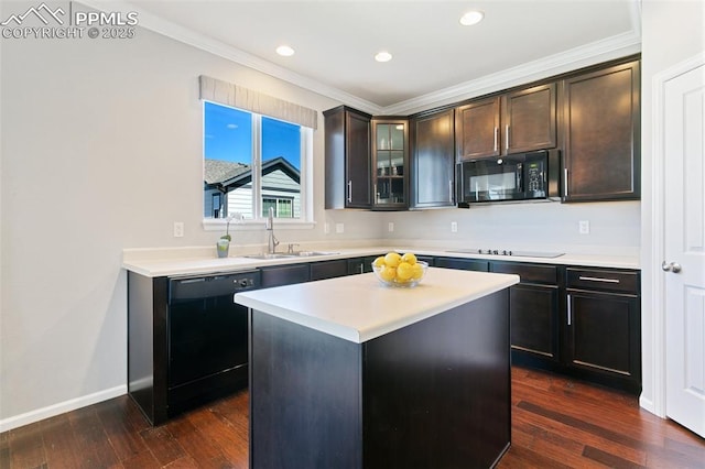 kitchen with black appliances, a sink, ornamental molding, light countertops, and glass insert cabinets