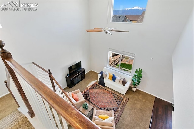 carpeted living area featuring a ceiling fan and a towering ceiling