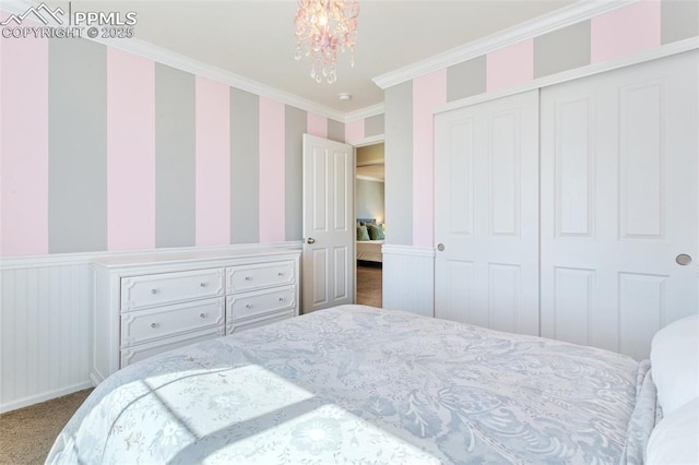 bedroom with carpet, wallpapered walls, crown molding, a closet, and a chandelier
