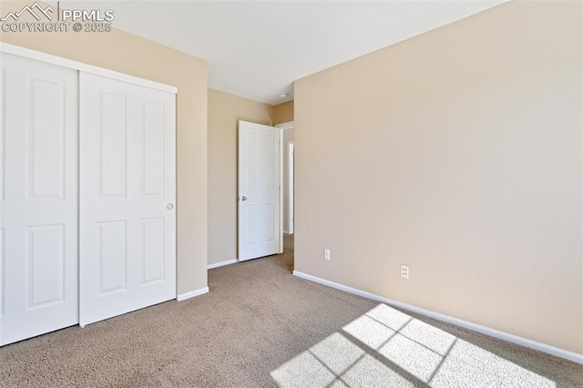 unfurnished bedroom featuring carpet, baseboards, and a closet