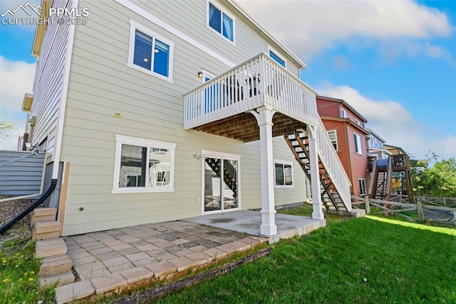 back of property with stairs, a wooden deck, a lawn, and a patio area