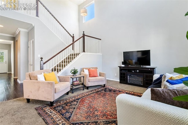 living area featuring ornamental molding, stairs, baseboards, carpet, and a towering ceiling