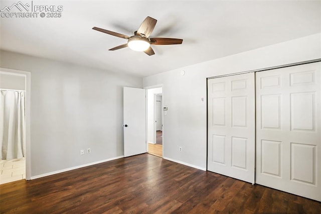 unfurnished bedroom with dark wood finished floors, baseboards, connected bathroom, a ceiling fan, and a closet
