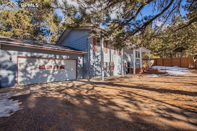 view of side of home featuring fence, an attached garage, and driveway