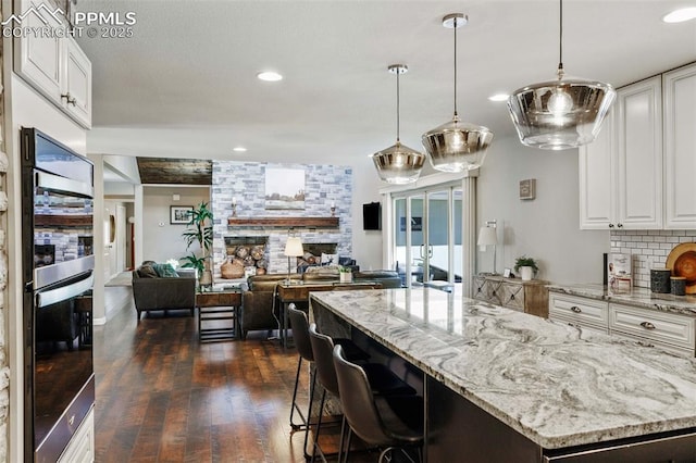 6940 Franciville Rd, Colorado Springs, CO 80908 - kitchen featuring a fireplace, dark wood-style flooring, light stone countertops, white cabinetry, and recessed lighting