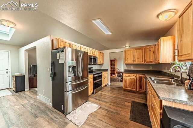 780 Foxwood Dr, Colorado Springs, CO 80911 - kitchen with appliances with stainless steel finishes, a sink, dark wood-style floors, dark countertops, and vaulted ceiling