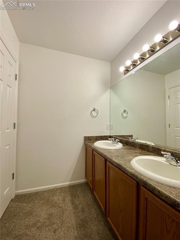 7513 Sandy Springs Pt, Fountain, CO 80817 - bathroom featuring double vanity, baseboards, and carpet flooring