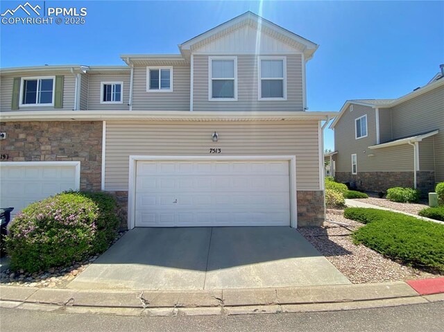 7513 Sandy Springs Pt, Fountain, CO 80817 - view of front facade featuring stone siding, an attached garage, and concrete driveway