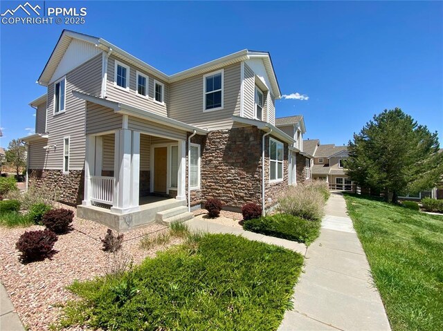 7513 Sandy Springs Pt, Fountain, CO 80817 - view of front facade featuring stone siding, covered porch, and a front yard