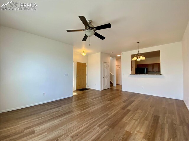 7513 Sandy Springs Pt, Fountain, CO 80817 - unfurnished living room featuring a chandelier, wood finished floors, baseboards, and ceiling fan