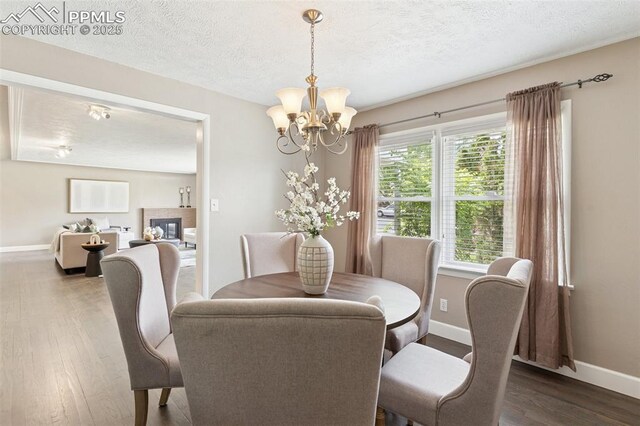 603 Three Eagles St, Colorado Springs, CO 80905 - dining space with baseboards, a chandelier, wood finished floors, a textured ceiling, and a glass covered fireplace