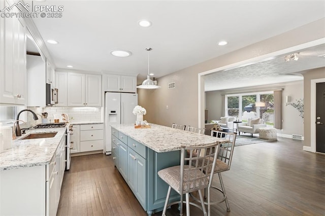 603 Three Eagles St, Colorado Springs, CO 80905 - kitchen with appliances with stainless steel finishes, white cabinetry, a breakfast bar area, dark wood-type flooring, and a kitchen island